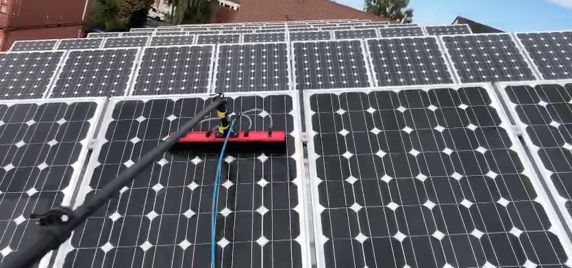 reihe-von-solar-paneelen-und-photovoltaikreinigung-mit-waschbuerste